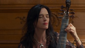 Movie still from “Happy End” (2017), directed by Michael Haneke – A woman with long black hair is holding a guitar; Close Up shot, Low angle