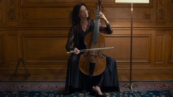 Movie still from “Happy End” (2017), directed by Michael Haneke – A woman in a black dress playing a cello; Medium shot, Low angle
