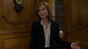 Movie still from “Happy End” (2017), directed by Michael Haneke – A woman in a black suit and white shirt; Medium shot, Over the shoulder angle