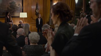 Movie still from “Happy End” (2017), directed by Michael Haneke – A group of people sitting in a room clapping; Wide shot, Over the shoulder angle