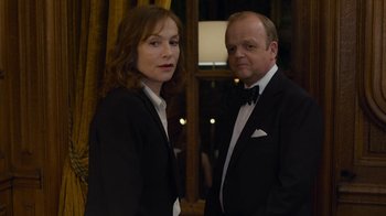 Movie still from “Happy End” (2017), directed by Michael Haneke – A man and a woman standing next to each other in tuxedos; Medium shot, Low angle