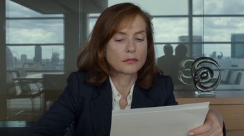 Movie still from “Happy End” (2017), directed by Michael Haneke – A woman sitting at a table looking at a paper; Close Up shot, Over the shoulder angle