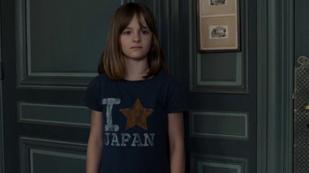 Movie still from “Happy End” (2017), directed by Michael Haneke – A young girl standing in front of a wall; Medium shot, High angle