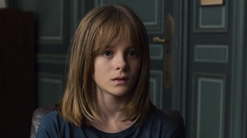 Movie still from “Happy End” (2017), directed by Michael Haneke – A young girl with long brown hair wearing a black t - shirt; Close Up shot, High angle
