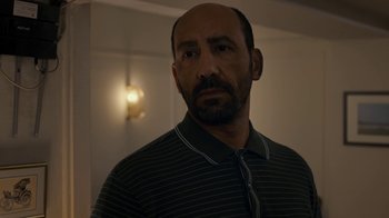 Movie still from “Happy End” (2017), directed by Michael Haneke – A man in a striped shirt is looking at the camera; Close Up shot, Over the shoulder angle