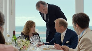 Movie still from “Happy End” (2017), directed by Michael Haneke – A man and a woman sitting at a table with a glass of wine; Medium shot, Over the shoulder angle