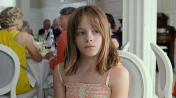 Movie still from “Happy End” (2017), directed by Michael Haneke – A young girl sitting in front of a group of diners; Close Up shot, High angle