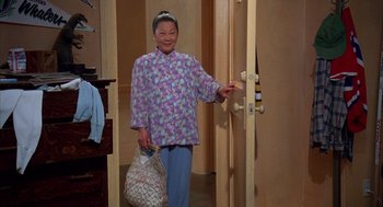 Movie still from “Happy Gilmore” (1996), directed by Dennis Dugan – An older asian woman holding a plastic bag and smiling; Wide shot, High angle