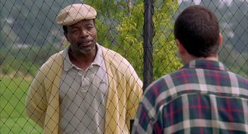 Movie still from “Happy Gilmore” (1996), directed by Dennis Dugan – A man wearing a hat talking to another man in a plaid shirt; Medium shot, Over the shoulder angle