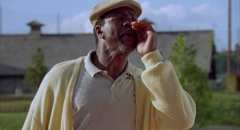 Movie still from “Happy Gilmore” (1996), directed by Dennis Dugan – An older man wearing a white shirt and a yellow hat; Close Up shot, Low angle