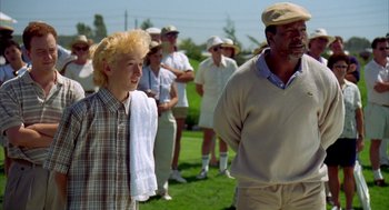 Movie still from “Happy Gilmore” (1996), directed by Dennis Dugan – A group of people standing on top of a grass covered field; Medium shot, Low angle