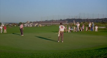 Movie still from “Happy Gilmore” (1996), directed by Dennis Dugan – A group of people standing on top of a lush green field; Extreme Wide shot, High angle