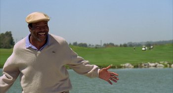 Movie still from “Happy Gilmore” (1996), directed by Dennis Dugan – An older man in a beige sweater and a hat is smiling; Medium shot, Low angle
