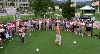 Movie still from “Happy Gilmore” (1996), directed by Dennis Dugan – A man swinging a golf club on a golf course; Extreme Wide shot, High angle