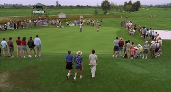 Movie still from “Happy Gilmore” (1996), directed by Dennis Dugan – A group of people standing on top of a lush green field; Extreme Wide shot, High angle