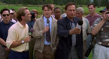 Movie still from “Happy Gilmore” (1996), directed by Dennis Dugan – A group of men standing around a field holding microphones; Medium shot, Low angle