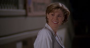 Movie still from “Happy Gilmore” (1996), directed by Dennis Dugan – A woman with short brown hair smiling for the camera; Close Up shot, Over the shoulder angle