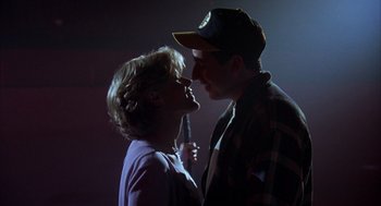 Movie still from “Happy Gilmore” (1996), directed by Dennis Dugan – A man and a woman kissing in a dark room; Medium shot, Low angle