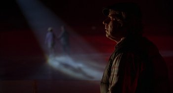 Movie still from “Happy Gilmore” (1996), directed by Dennis Dugan – A man standing in front of a projection screen; Medium shot, Low angle