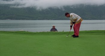 Movie still from “Happy Gilmore” (1996), directed by Dennis Dugan – A man is playing a game of golf while another man watches; Extreme Wide shot, Over the shoulder angle