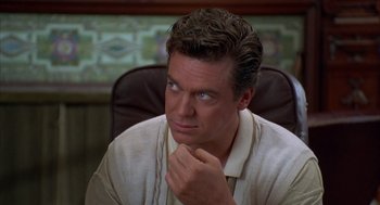 Movie still from “Happy Gilmore” (1996), directed by Dennis Dugan – A person sitting in a chair with his hand under his chin; Close Up shot, High angle