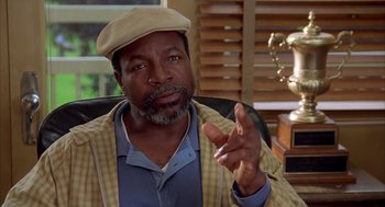 Movie still from “Happy Gilmore” (1996), directed by Dennis Dugan – An older man wearing a tan hat and a yellow jacket; Close Up shot, Low angle