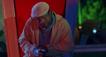 Movie still from “Happy Gilmore” (1996), directed by Dennis Dugan – A man with a white hat is holding a remote control; Medium shot, Low angle