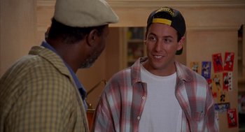 Movie still from “Happy Gilmore” (1996), directed by Dennis Dugan – A man wearing a hat talking to another man in front of a mirror; Medium shot, Over the shoulder angle
