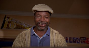 Movie still from “Happy Gilmore” (1996), directed by Dennis Dugan – A man wearing a hat and smiling for the camera; Close Up shot, Low angle