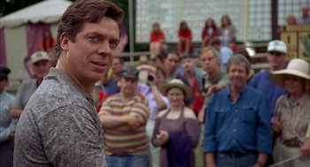 Movie still from “Happy Gilmore” (1996), directed by Dennis Dugan – A man standing in front of a group of people; Close Up shot, Over the shoulder angle