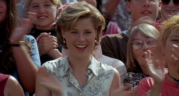 Movie still from “Happy Gilmore” (1996), directed by Dennis Dugan – A woman smiling while standing in a crowd of onlookers; Close Up shot, Over the shoulder angle