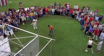 Movie still from “Happy Gilmore” (1996), directed by Dennis Dugan – A group of people standing in a circle on a field; Extreme Wide shot, High angle
