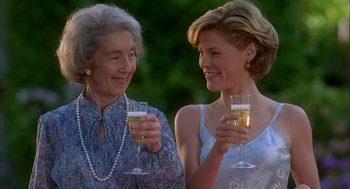 Movie still from “Happy Gilmore” (1996), directed by Dennis Dugan – Two women are holding wine glasses and smiling for the camera; Medium shot, Over the shoulder angle