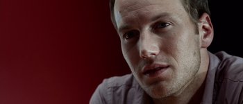 A man's face in front of a red background