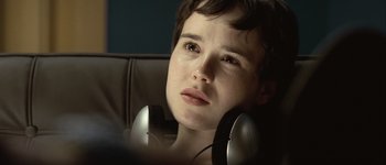 Movie still from “Hard Candy” (2005), directed by David Slade – A young boy wearing headphones and sitting in a chair; Close Up shot, Over the shoulder angle