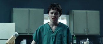 Movie still from “Hard Candy” (2005), directed by David Slade – A person wearing a green shirt in a room; Close Up shot, Over the shoulder angle