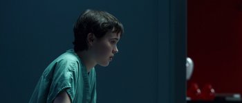 Movie still from “Hard Candy” (2005), directed by David Slade – A young boy looking into the distance in a dark room; Close Up shot, Over the shoulder angle