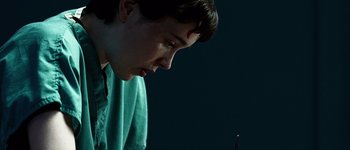 A person looking at a candle in a dark room