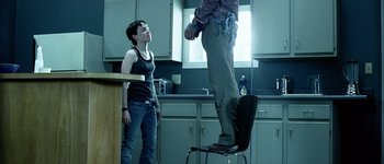 Movie still from “Hard Candy” (2005), directed by David Slade – A man standing on top of a chair next to a woman; Wide shot, Low angle