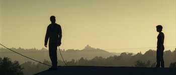 Movie still from “Hard Candy” (2005), directed by David Slade – A man standing on the side of a road holding a whip; Extreme Wide shot, Low angle