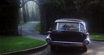 Movie still from “Harold and Maude” (1971), directed by Hal Ashby – A car driving down a road near a forest; Wide shot, High angle