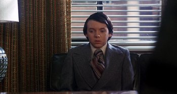 Movie still from “Harold and Maude” (1971), directed by Hal Ashby – A man in a suit and tie sitting at a table; Medium shot, Over the shoulder angle