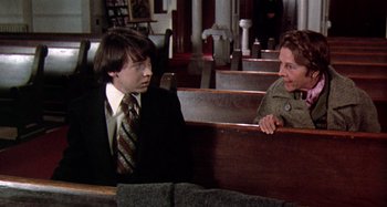 Movie still from “Harold and Maude” (1971), directed by Hal Ashby – Two people sitting in a pew talking to each other; Medium shot, Over the shoulder angle