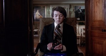 Movie still from “Harold and Maude” (1971), directed by Hal Ashby – A man in a suit and tie holding a cell phone; Medium shot, Low angle
