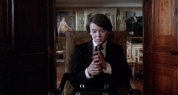 Movie still from “Harold and Maude” (1971), directed by Hal Ashby – A man in a suit and tie holding a tie; Medium shot, Low angle