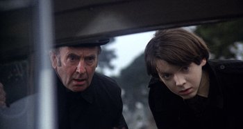 Movie still from “Harold and Maude” (1971), directed by Hal Ashby – A man and a boy looking out of a car window; Medium shot, Over the shoulder angle