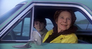 Movie still from “Harold and Maude” (1971), directed by Hal Ashby – An older woman and a young boy sitting in the drivers seat of a car; Medium shot, Over the shoulder angle