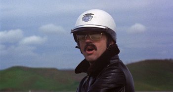 Movie still from “Harold and Maude” (1971), directed by Hal Ashby – A man wearing a white helmet and a leather jacket; Close Up shot, Low angle