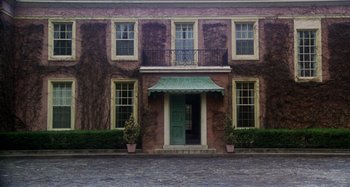Movie still from “Harold and Maude” (1971), directed by Hal Ashby – A green front door of a building with a balcony; Extreme Wide shot, Low angle