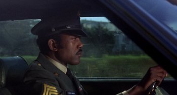 Movie still from “Harold and Maude” (1971), directed by Hal Ashby – A man in a uniform driving a car; Medium shot, Low angle